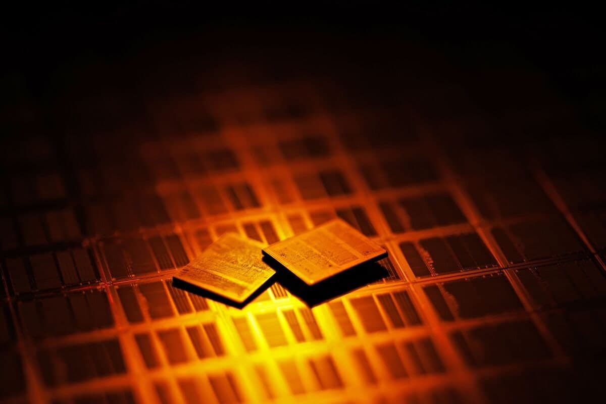 Two semiconductor chips glowing under orange light on a circuit board pattern