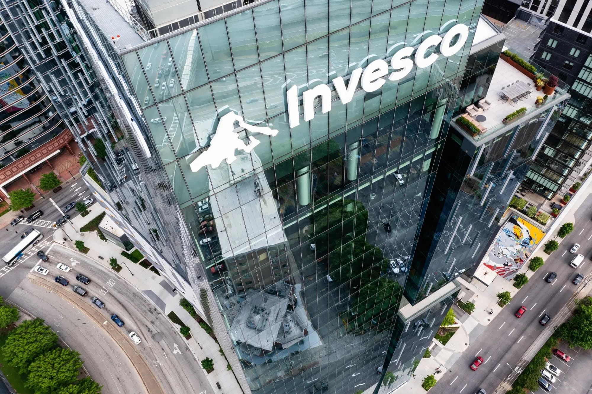 An aerial view looking down on the Invesco logo displayed on the glass facade of a high rise office tower